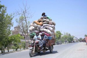 A person sitting on luggage loaded on tricycle loader rickshaw on the way at Chungi No.9