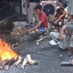 Vendor cleaning head and feet of sacrificial animals with the help of burner at Jhang Bazaar