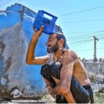 A person bathing under tanker during scorching hot weather at Zia Masjid