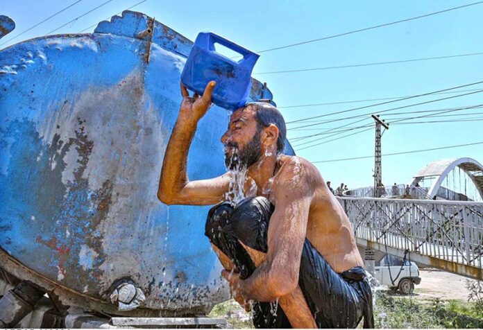 A person bathing under tanker during scorching hot weather at Zia Masjid