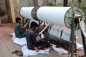 Workers of power loom factory busy in their routine work.