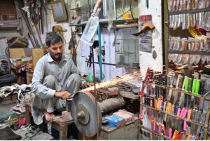 A blacksmith busy in sharpening knives to be used for slaughtering sacrificial animals during upcoming Eid ul Azha