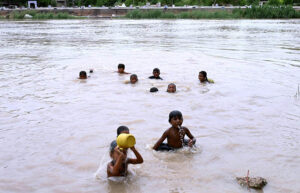 Children enjoy bathing to get relief for scorching weather in the city at Phuleli canal.