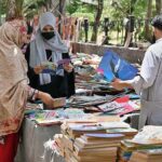 Women selecting old books from a roadside stall at Mall Road