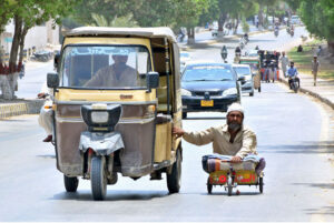 A disable person on his cart holding rickshaw while travelling on road to reach his destination.