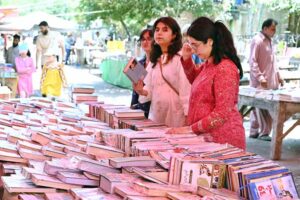 Women busy in selecting and purchasing old books from roadside stall at Mall Road.