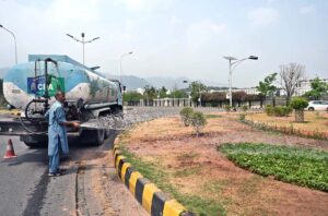 CDA worker busy in showering water on plants in front of Parliament House.