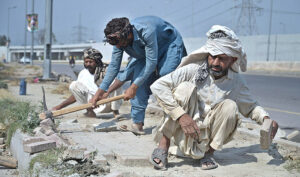 Labourers busy in fixing cemented tiles on footpath along Park Road in Federal Capital.