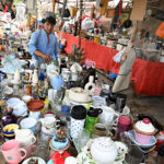 Vendor displaying slippers and sandals to attract the customer at Makki Shah road