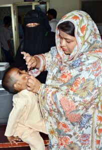 Lady Health Worker administering polio drops to a child during anti polio campaign in the city.