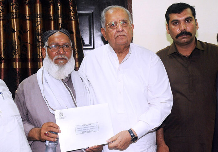 Federal Minister for Housing and Works, Mian Riaz Hussain Pirzada, giving a letter from the Prime Minister to the father of Shaheed Sepoy Asad Ullah at his residence