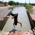 Youngster diving in a canal for bath to get relief from hot weather