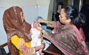 Lady Health Worker administering polio drops to a child during anti polio campaign in the city.