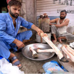 Butchers cleaning sacrificial animal legs called Paye during the Eid al-Adha at Qissa Khawani Bazar