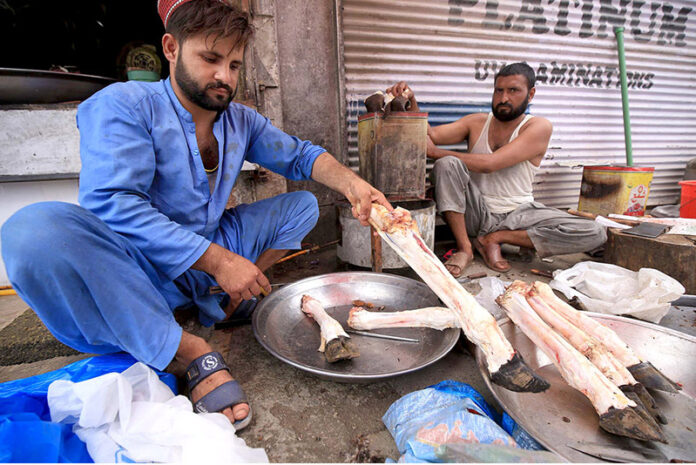 Butchers cleaning sacrificial animal legs called Paye during the Eid al-Adha at Qissa Khawani Bazar