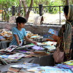 A woman with her child selecting old books from a road side stall at Mall Road