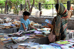 A woman with her child selecting old books from a road side stall at Mall Road