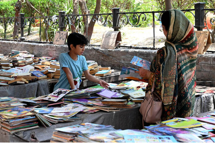 A woman with her child selecting old books from a road side stall at Mall Road