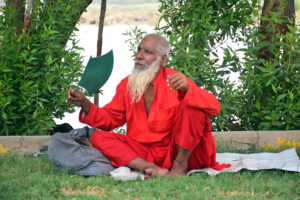 An elderly man fanning himself with a hand fan at green belt during the scorching weather in the city