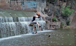 Youngsters jump into a stream of water to beat the heat at Angoori during a extreme hot weather