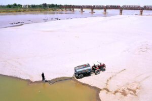 Driver filling their water tanker at Indus river during scorching heat in the city