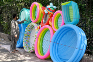 Vendor selling and displaying inflatable swimming pools to attract the customers at roadside setup