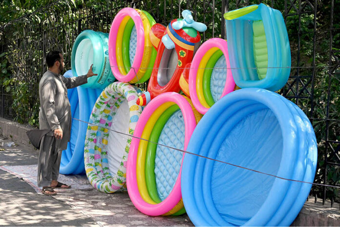 Vendor selling and displaying inflatable swimming pools to attract the customers at roadside setup