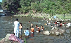 Youngsters jump into a stream of water to beat the heat at Angoori during a extreme hot weather