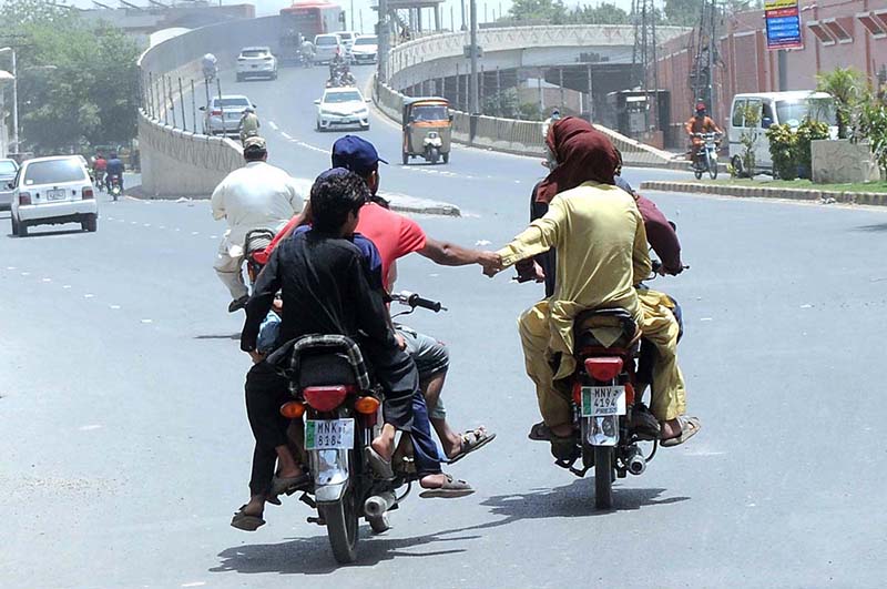 A pillion rider holding the hand of another motorcyclist, heading towards a petrol pump for refueling A pillion rider holding the hand of another motorcyclist, heading towards a petrol pump for refueling