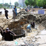 Labourers busy in construction work of manhole at Latifabad during development work in the city