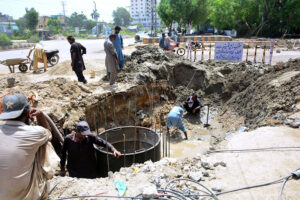 Labourers busy in construction work of manhole at Latifabad during development work in the city