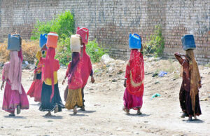 Gypsy women carries pots on their head, having journeyed to far-flung areas to fetch clean water at Qasimabad,Rural communities still grapple with the enduring challenge of access to water.