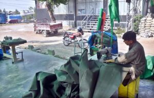 Tailor busy sewing Tarpaulin at his roadside setup in the City