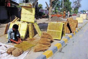 Worker is busy filling husk in frames of air coolers at his workplace.