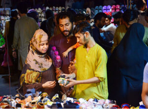 Family busy in selecting and purchasing sandal on a roadside stall in connection with Eid-ul-Azha at Resham Bazaar.