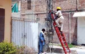 Staff of MEPCO fixing electricity fault on a tower at roadside in the city.