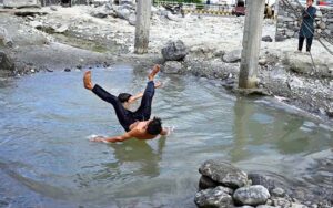 Youngsters jumping and bathing in water pound to get some relief from hot weather in the city.