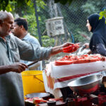 A vendor selling watermelon to attract the customers at his roadside setup