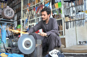 A blacksmith is busy sharpening knives to be used for slaughtering sacrificial animals for the upcoming Eid Ul Adha.