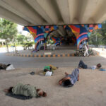 Homeless people take a rest under a bridge to protect them from the scorching heat as the city is witnessing high temperature