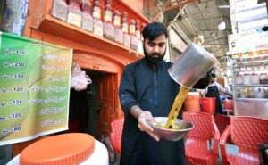 A vendor preparing and selling traditional summer drinks for customers at his roadside setup near Namak Mandi.