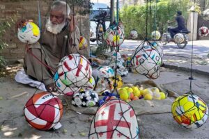 A vendor busy in filling air in footballs to attract customers at his roadside setup in Provincial Capital.