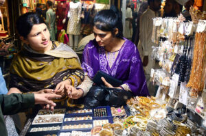 Family busy in selecting and purchasing sandal on a roadside stall in connection with Eid-ul-Azha at Resham Bazaar.