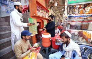 A vendor preparing and selling traditional summer drinks for customers at his roadside setup near Namak Mandi.