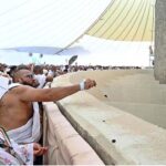Hajj pilgrims throwing pebbles at three pillars that represent Satan at Jamarat while performing Hajj ritual
