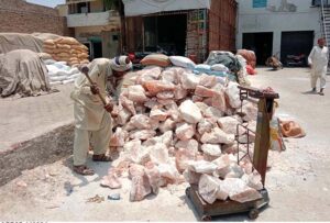 Laborer is busy crushing the salt pieces with the help of hammer.