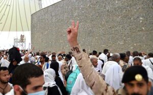 Hajj pilgrims throwing pebbles at three pillars that represent Satan at Jamarat while performing Hajj ritual