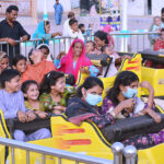 Families with children enjoying the mechanical swing ride at fun land park on the 3rd day of Eidul Azha festival