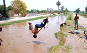 Children swim and dive into the canal, seeking relief from the intense heat