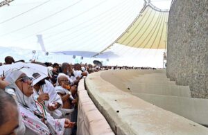 Hajj pilgrims throwing pebbles at three pillars that represent Satan at Jamarat while performing Hajj ritual